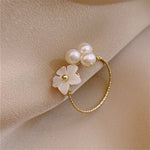 Justerbar ring med hvide kronblade og perler i guld