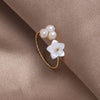 Justerbar ring med hvide kronblade og perler i guld